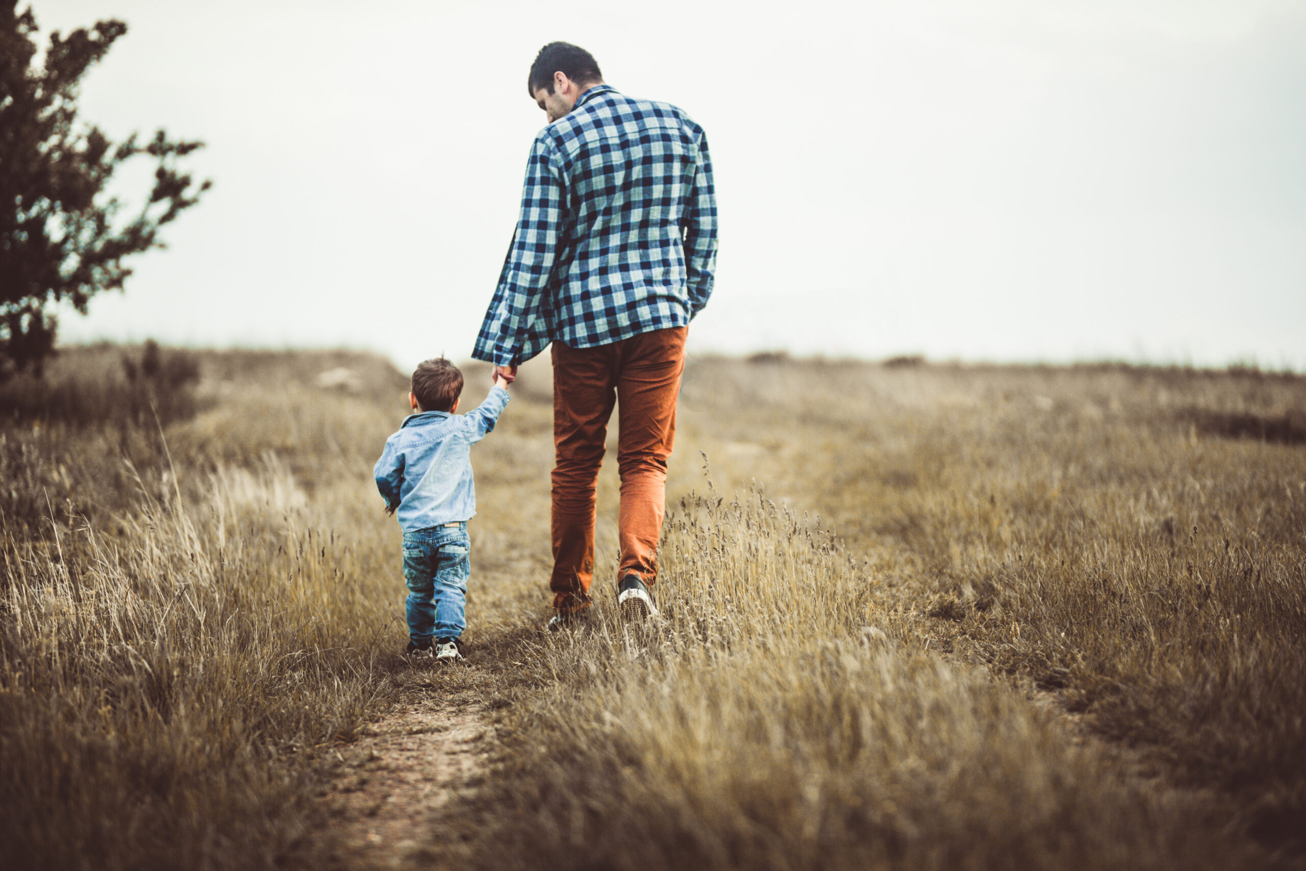 Father and son walking on an emoty country road and holding hands